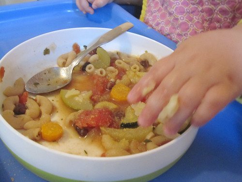 Young child eating soup with pasta